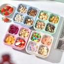 Colorful compartmentalized snack trays with various snacks on a light surface.
