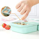 Green food storage container with an easy-open lid, hand reaching in to open it, strawberries on the side.