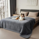 Dog sitting on a bed with a gray blanket in a bedroom
