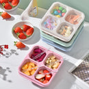 Colourful snack containers with compartments filled with fruits and snacks on a light surface.